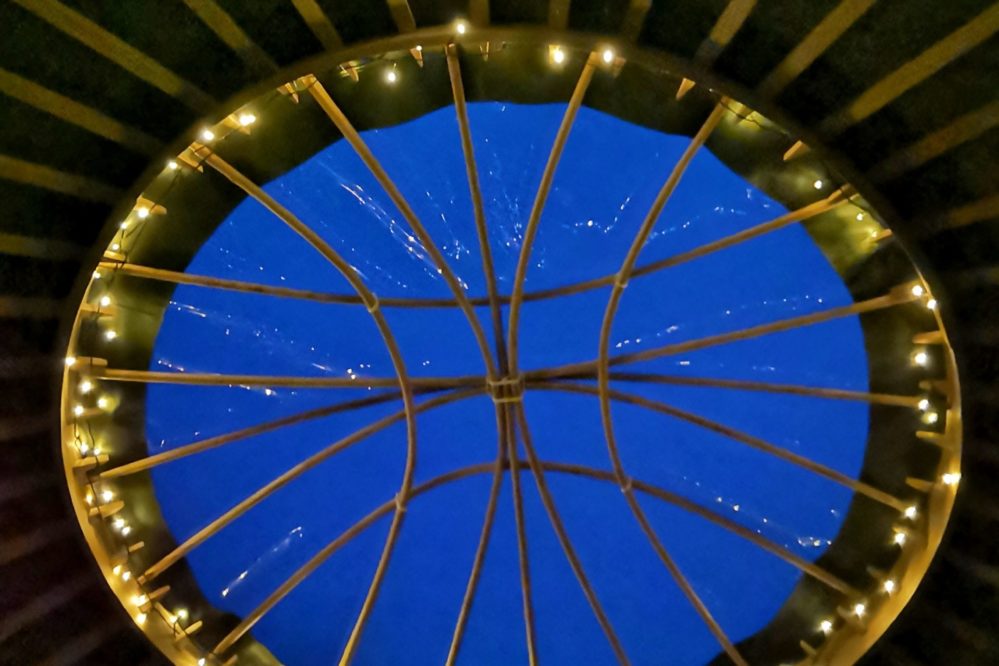 Blue night sky showing through fairy lights on the yurt crown