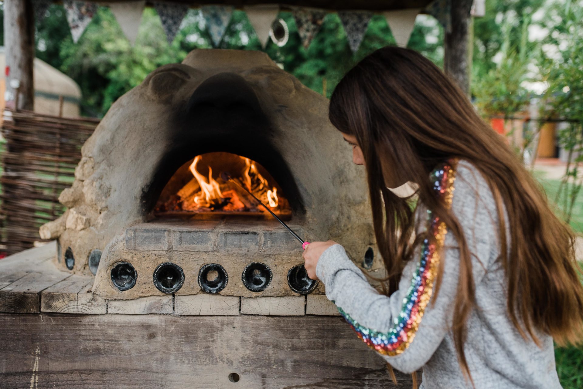 Flames inside the cob oven and girl toasting marshmallows