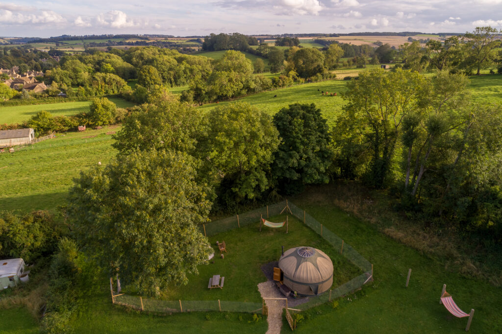 Glamping in Gloucestershire: Aerial photo of a yurt surrounded by a wire fence and green fields