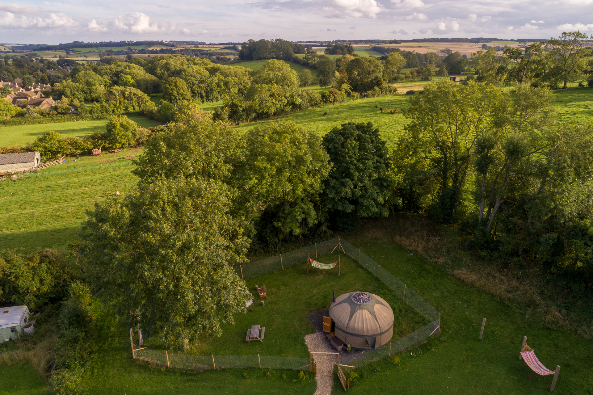 Glamping in Gloucestershire: Aerial photo of a yurt surrounded by a wire fence and green fields