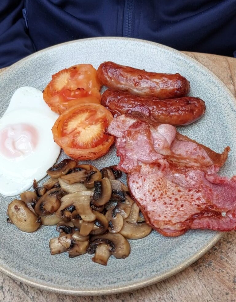 Breakfast plate of sausage, bacon, eggs, tomatoes nad mushrooms